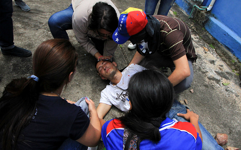 Demonstrators help an injured man during clashes between security forces and protesters April 5 in San Cristobal, Venezuela. (CNS/Reuters/Carlos Eduardo Ramirez)