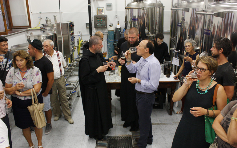 Benedictine monks mingle with guests during a tasting Aug. 14 in the brew room of St. Benedict's Monastery in Norcia, Italy. (CNS/Henry Daggett)