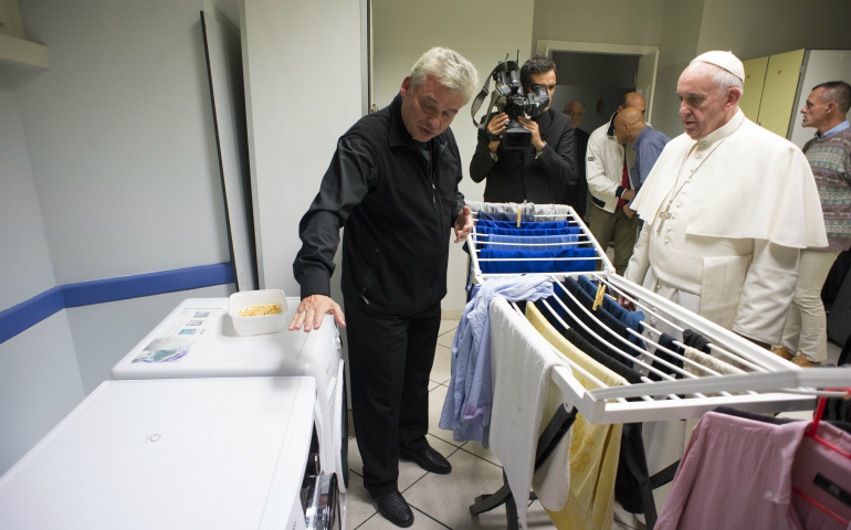 Pope Francis listens as Archbishop Konrad Krajewski, the papal almoner, offers an explanation during the pope's visit to a new homeless shelter for men in Rome Oct. 15. Housed in a Jesuit-owned building, the shelter was created by and is run with funds from the papal almoner. (CNS photo/L'Osservatore Romano, handout)