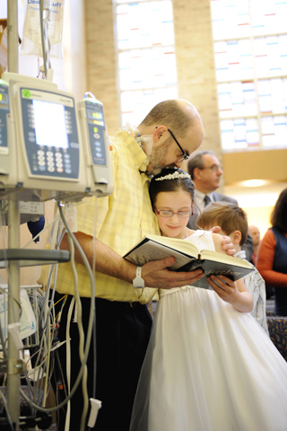 Tim Day kisses his 8-year-old daughter Erin during her first Communion Mass on April 26 at Strong Memorial Hospital in Rochester, N.Y. (CNS/Catholic Courier/Mike Crupi)