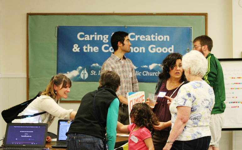 Tyler Wagner working a table about ecological justice for the parish at a community picnic. (Raymond Garcia)