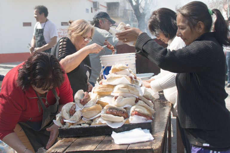 Residents of Villa 21 share choripanes, a traditional chorizo sandwich, following a Mass Sept. 5. (Horacio "Tati" di Renzi)