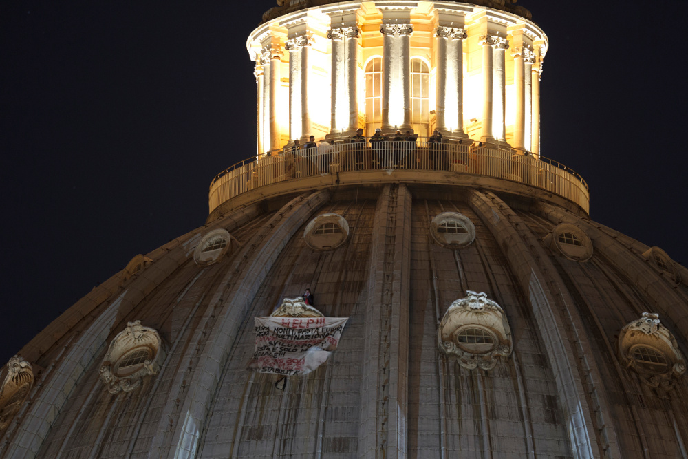 Firemen stand above a protester perched atop a window on the dome of St. Peter's Basilica on Tuesday at the Vatican. (CNS/Paul Haring) 