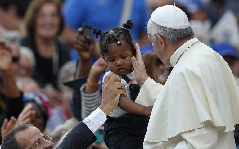 Pope Francis greets a child as he arrives to lead his general audience Wednesday in St. Peter's Square at the Vatican. (CNS/Paul Haring)