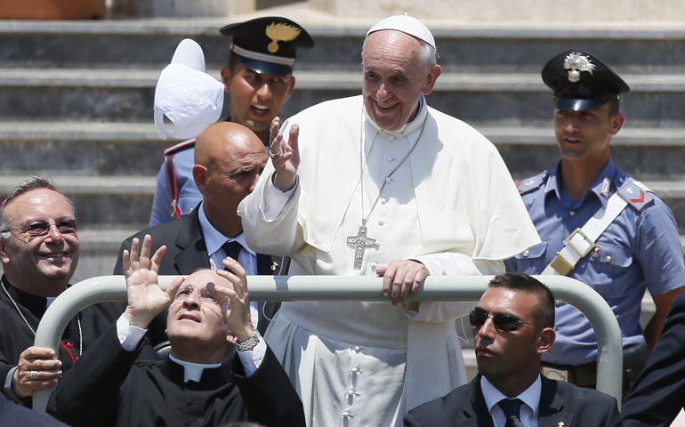 A cap is thrown toward Pope Francis as he leaves in a jeep July 8 after visiting San Gerlando Church in Lampedusa, Italy. The pope's personal secretary, Msgr. Alfred Xuereb, left, caught the cap. (CNS/Paul Haring)