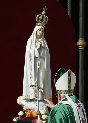 Pope Francis touches a statue of Our Lady of Fatima at the start of a Mass in honor of Mary on Oct. 13, 2013, in St. Peter's Square at the Vatican. (CNS/Paul Haring)