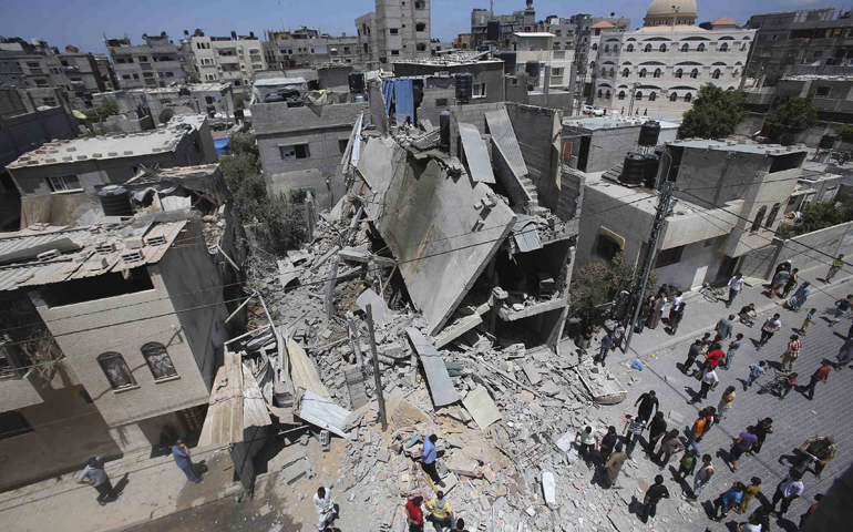 Palestinians in Rafah, Gaza Strip, gather around the remains of a house that police said was destroyed in an Israeli airstrike. (CNS/Ibraheem Abu Mustafa)