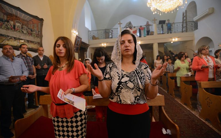 Catholic Suheir Saliba, left, prays beside her Greek Orthodox sister-in-law, Maha Kamal, during the Easter Divine Liturgy on Sunday in the St. George Greek Orthodox Church in Jifna, West Bank. (CNS/Debbie Hill)