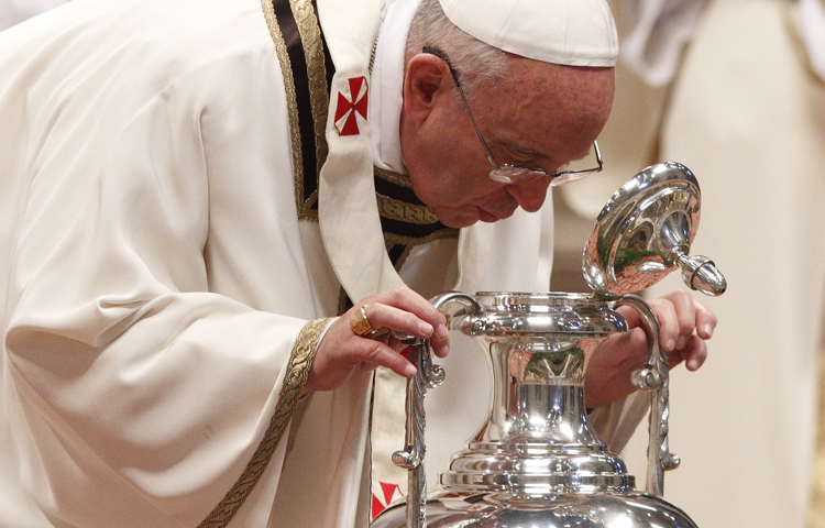 Pope Francis breathes over chrism oil, a gesture symbolizing the infusion of the Holy Spirit, during Holy Thursday chrism Mass Thursday in St. Peter's Basilica at the Vatican. (CNS/Paul Haring)
