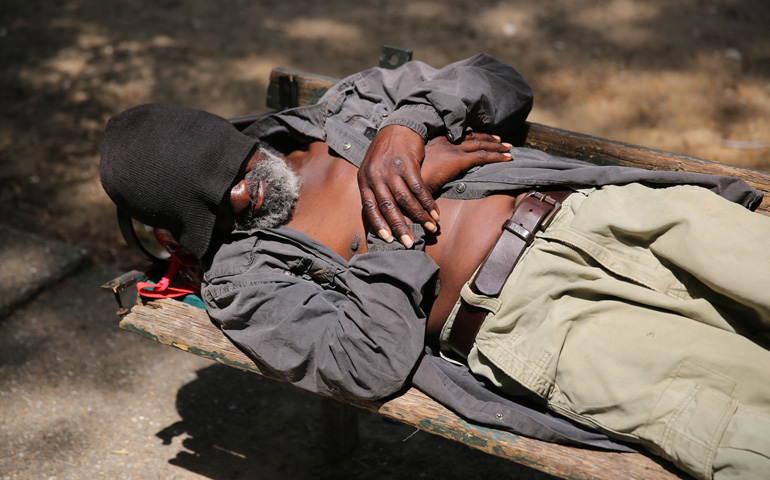 A homeless man rests on a bench in a park outside St. Vincent de Paul Church in downtown Baltimore in early July. (CNS/Bob Roller) 