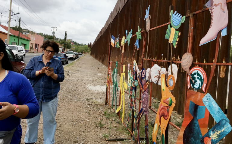 The fence as far as the eye can see, decorated defiantly (Mary Ann McGivern)