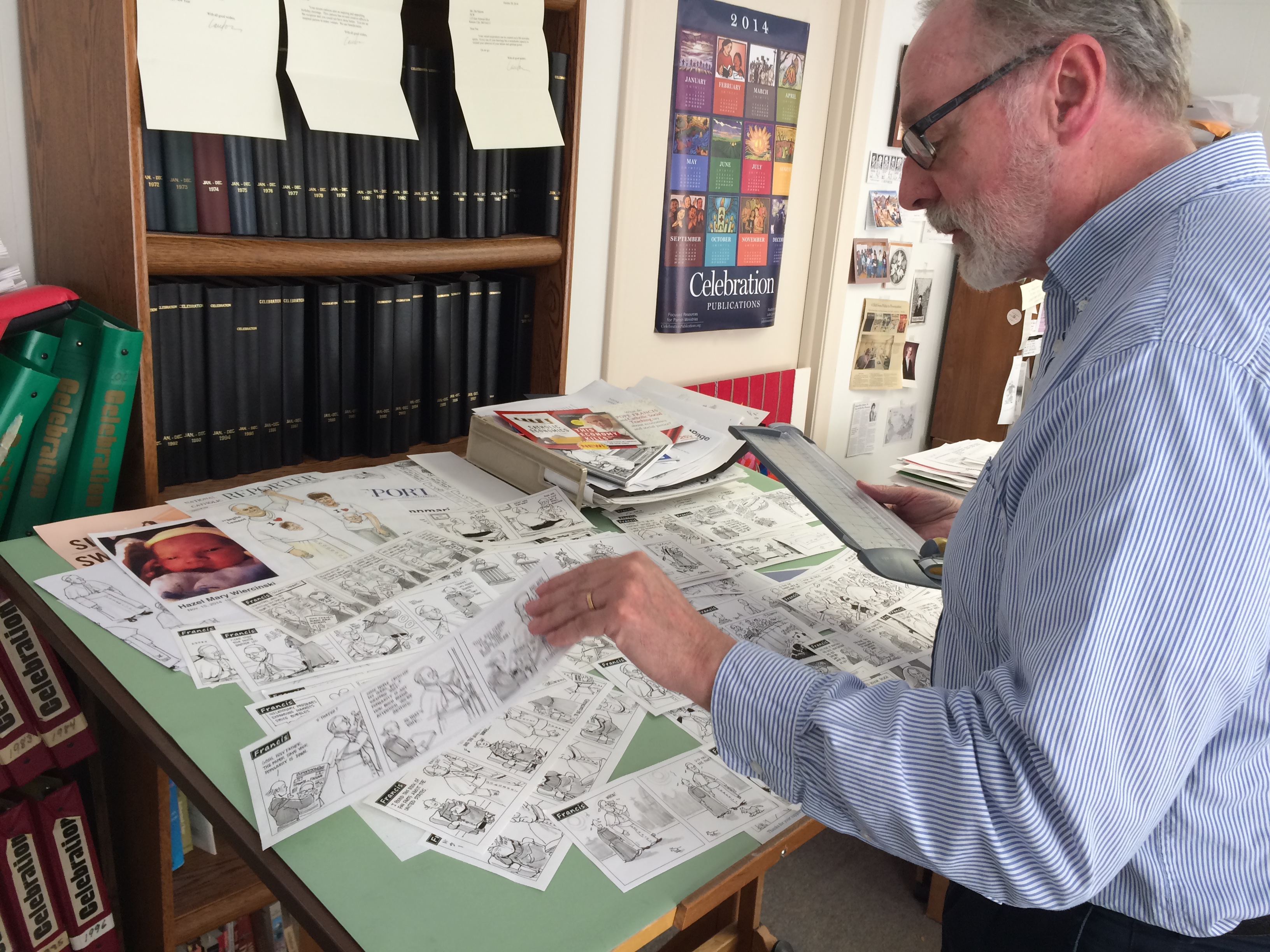 Marrin checks latest Francis strips in his Celebration office (NCR photo/Tom Fox)