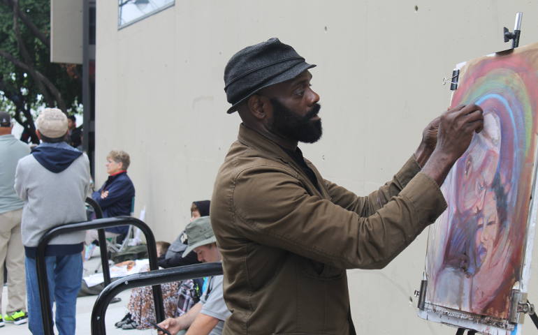 Kevin Johnson of Phildelphia paints a portrait of Pope Francis while pilgrims along Benjamin Franklin Parkway watched. (NCR photos/Brian Roewe)