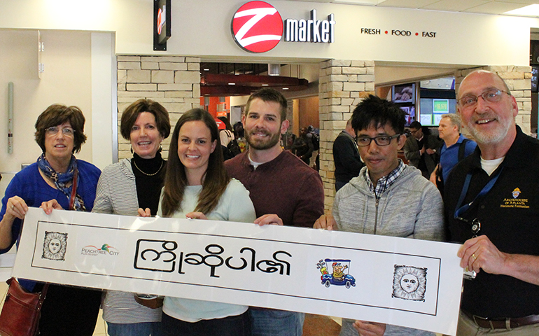 Volunteers to welcome the refugee family April 15 at Hartsfield-Jackson Atlanta International Airport, holding a sign which says "Welcome" in Burmese. (Jennifer Harmeling)