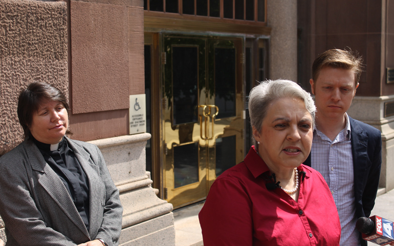 Colleen Simon addresses the media about her lawsuit at a press conference Thursday outside the chancery offices of the Kansas City-St. Joseph, Mo., diocese. Also pictured are her lawyer, E.E. Keenan, right, and her wife, the Rev. Donna Simon. (NCR Photo/Brian Roewe)