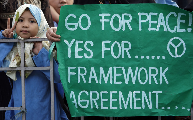 A Muslim girl in Manila, Philippines, flashes the peace sign after watching the Oct. 14 arrival of a nationwide peace caravan supporting the signing of a framework agreement between the government and Muslim rebels. (CNS/Reuters/Cheryl Ravelo)