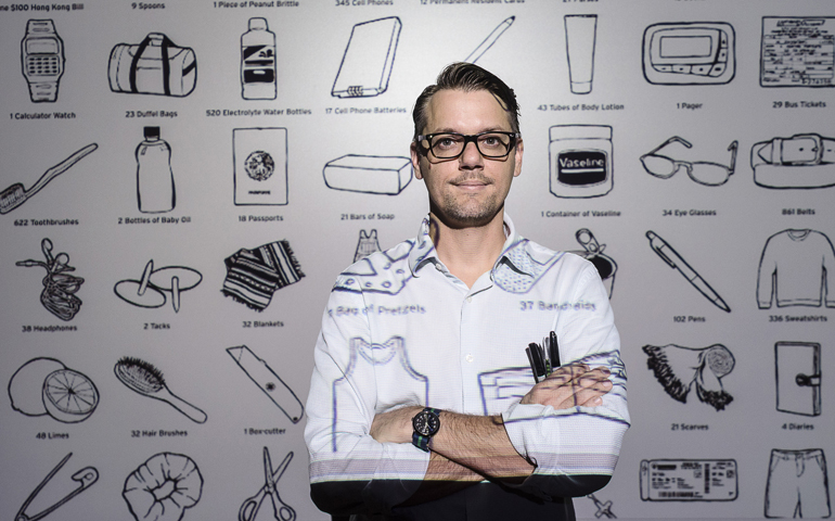 Graphic designer John Stobbe of Tucson, Ariz., stands in front of a poster Aug. 13 he designed for the Colibri Center for Human Rights using images of possessions found on the bodies of border crossers who have died in the Arizona desert. (CNS/Gary O'Brien)