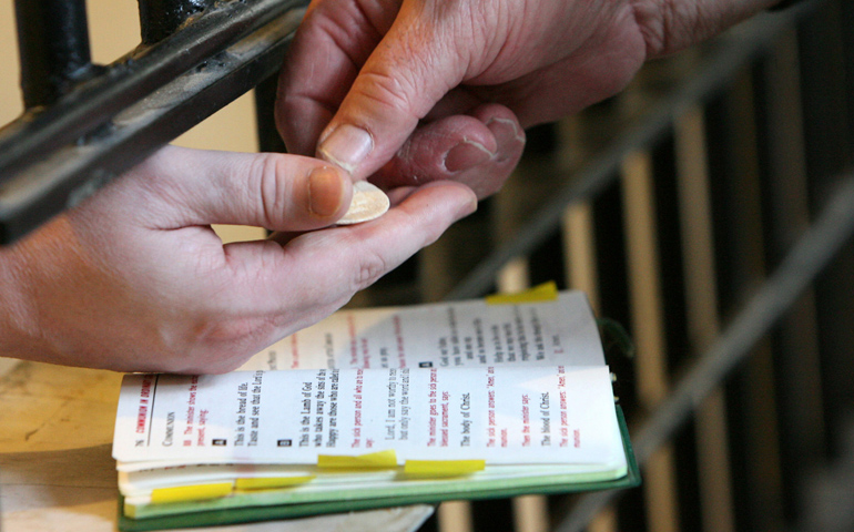 A deacon distributes Communion to a death-row inmate at Indiana State Prison in Michigan City, Ind. (CNS/Northwest Indiana Catholic/Karen Callaway)