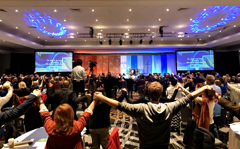 People sing "We Shall Overcome" during the NEXT Church gathering in Kansas City, Missouri, in March. (Jen James)