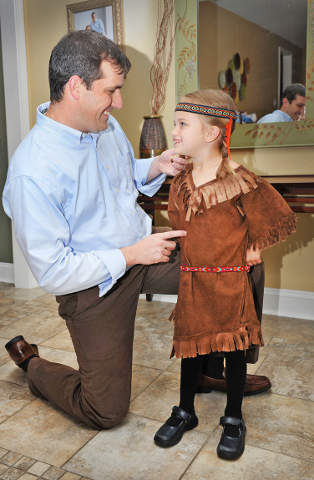 Katherine Kateri Howat, dressed as a Mohawk princess, displays the outfit for her father, Cory Howat, Oct. 11 at their home in Metairie, La. The 4-year-old and her father will be among thousands of U.S. pilgrims making a trip to Rome for the Oct. 21 cano nization of Blessed Kateri Tekakwitha, known as the "Lily of the Mohawks." (CNS photo/Frank J Methe, Clarion Herald) 