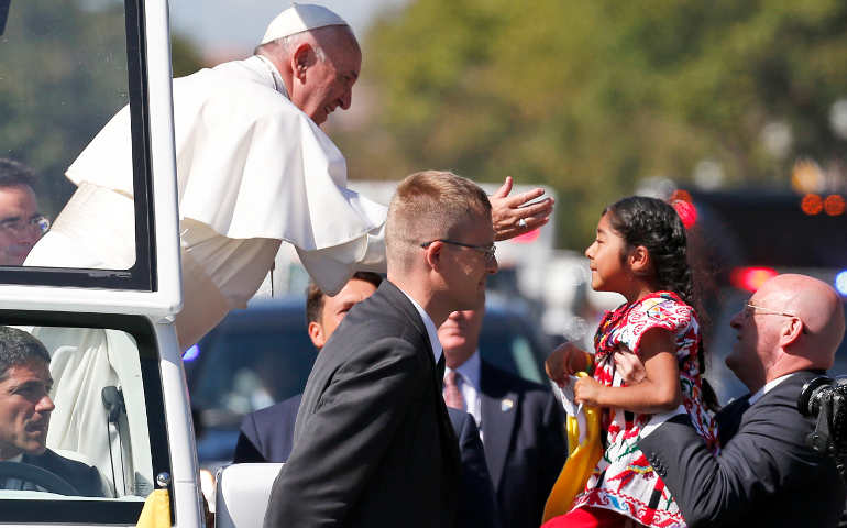Pope Francis reaches from the popemobile as a child is brought to him along a parade route Sept. 23 in Washington. (CNS photo/Alex Brandon, pool)