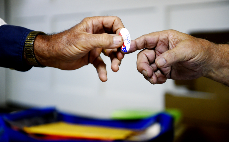 A poll volunteer hands out an "I Voted" sticker at a rural polling place during the U.S. presidential election in Stillwater, Okla., Nov. 8. (Newscom/Reuters/Nick Oxford)