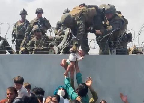 A baby is handed over to a U.S. Army soldier over the perimeter wall of Hamid Karzai International Airport Aug. 19 in Kabul, Afghanistan. (CNS/Omar Haidari, social media via Reuters)