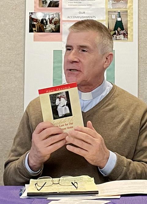 Jesuit Fr. Lorn Snow holds a copy of Laudato Si' during the March 21 event at Gesu Catholic Church in Detroit. (Amy Ketner)