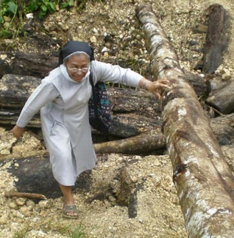 Missionary Benedictine Sr. Edita Eslopor climbs to visit an Indigenous Lumad village in the Philippines after an hourlong motorcycle ride. (Courtesy of Rural Missionaries of the Philippines)