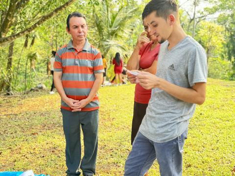 A group of teenagers, accompanied by Julio Rivera, left, a survivor of the Sumpul River massacre, read a story on April 27 in Arcatao, El Salvador, to learn about the ambush and murder of more than 600 peasants in the nearby Sumpul River in 1980. (GSR photo/Rhina Guidos)