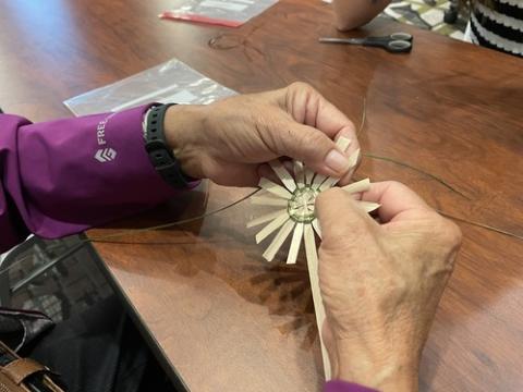 Tekakwitha Conference, 2024. Woman's hands shown weaving sweetgrass.