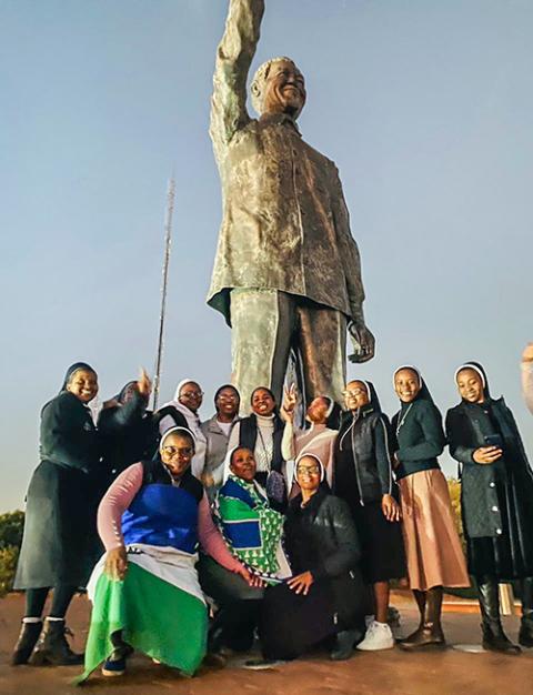 Sisters pose in front of a statue of Nelson Mandela at Naval Hill in Bloemfontein, South Africa, on June 15, during a tour that was part of the Winter School program. (Lipalesa Mothamane)