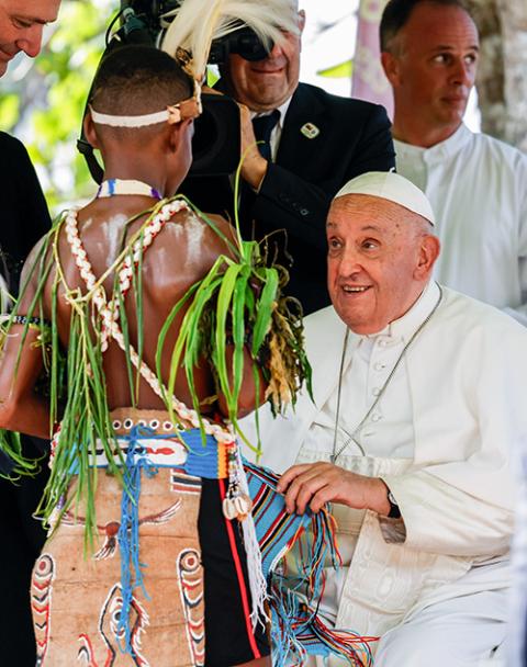 Pope Francis receives a gift from a child in traditional dress at the Holy Trinity Humanistic School in Baro, Papua New Guinea, Sept. 8. (CNS/Vatican Media)