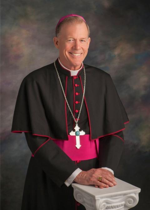 Archbishop John C. Wester of Santa Fe. Formal portrait of Wester, standing in bishop's choir dress, hands folded and resting on short ionic column.