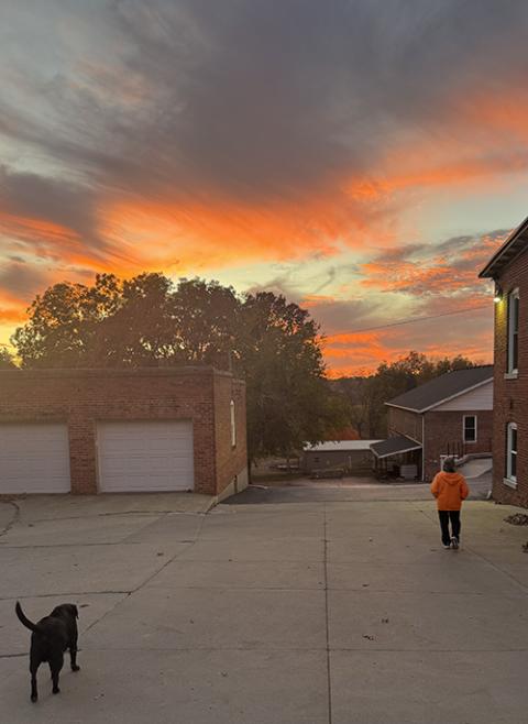La autora Helen Mueting pasea con Sophie, la perra labrador negra de las hermanas, en el monasterio benedictino de Atchison, Kansas, Estados Unidos, con el atardecer otoñal como telón de fondo. (Foto: cortesía Helen Mueting)