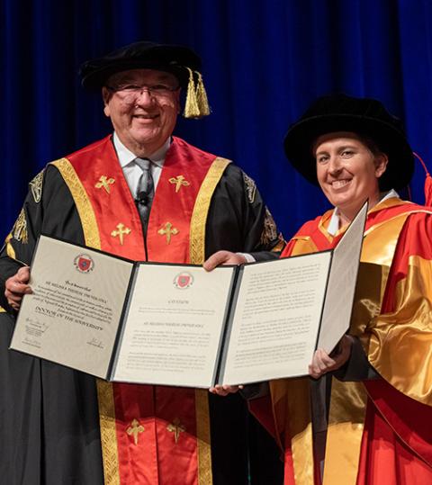 Sister Dwyer poses with her honorary doctorate degree, dressed in cap and gown.