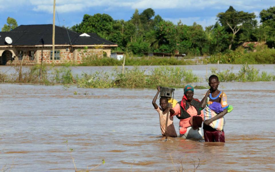 A boy and young man help a woman wade through floodwaters in Busia, Kenya, May 3, 2020. Some African Catholic advocates believe the church needs to do more to advance the ideas in Pope Francis' 2015 encyclical, "Laudato Si'." (CNS photo/Thomas Mukoya, Reu