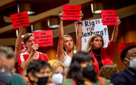 Parents and residents stand to oppose the county's K-6 school mask mandate after public comment finished as more than 100 people pack the Harris Auditorium at a Genesee County Board of Commissioners meeting Aug. 30, 2021.