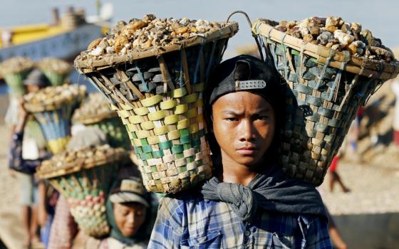 Children in Yangon, Myanmar, carry baskets loaded with gravel used for construction in 2015. (CNS/EPA/Rungroj Yongrit)