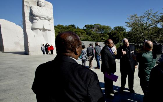 Bishop George Murry (facing camera, right), chair of the U.S. bishops' Ad Hoc Committee Against Racism, conducts an interview near the Martin Luther King Jr. Memorial in Washington Oct. 2. (CNS/Tyler Orsburn)