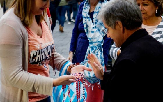 Fr. Paul Felix blesses rosaries Oct. 27 outside Houston's Annunciation Catholic Church, which sits across the street from Minute Maid Park where the Houston Astros hosted the Los Angeles Dodgers during the 2017 World Series. (CNS/Texas Catholic Herald)