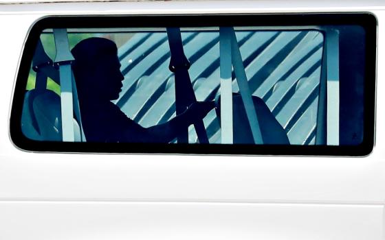 A minor sits in the back of a van July 11 as he is transported into Casa Esperanza, a federally contracted shelter in Brownsville, Texas. (CNS/Reuters/Carlos Barria)