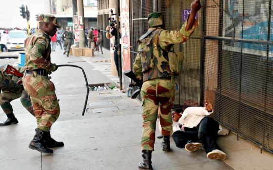 Soldiers beat a female supporter of the MDC Alliance opposition party of Nelson Chamisa outside the party's headquarters as they await the results of the general elections Aug. 1 in Harare, Zimbabwe. (CNS/Reuters/Mike Hutchings)