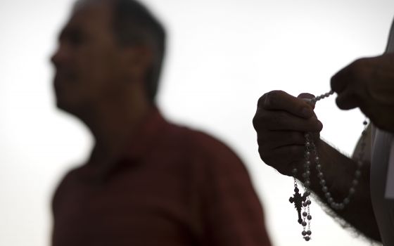 An attendee prays the rosary Oct. 1 during a public session on the issue of clergy sexual abuse at Our Mother of Confidence Parish Hall in San Diego. (CNS/David Maung)