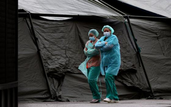Medical staff wearing protective face masks and suits walk past a tent at Madrid's Gregorio Maranon Hospital April 1, amid the COVID-19 pandemic. (CNS / Reuters / Susana Vera)