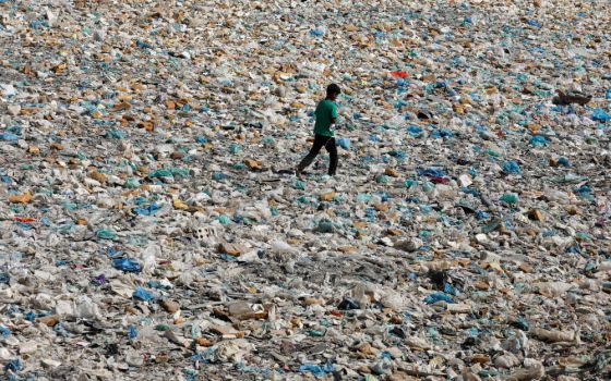 A boy walks over a drainage channel littered with garbage in Karachi, Pakistan, on Earth Day April 22, 2020. (CNS photo/Akhtar Soomro, Reuters)