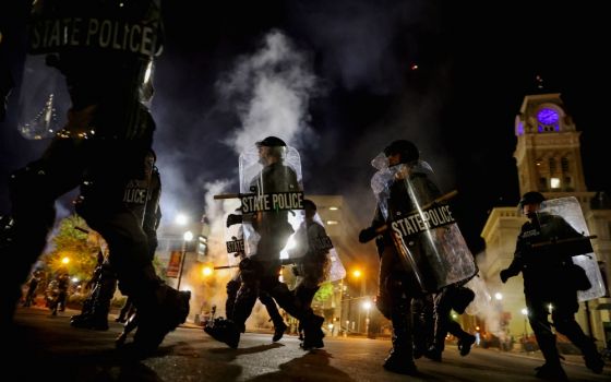 Police officers in Louisville, Kentucky, move past city hall Sept. 23 to clear protesters from a plaza ahead of a 9 p.m. curfew. (CNS/Reuters/Carlos Barria)