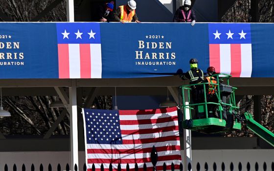 Workers in Washington place Biden-Harris inauguration banners on the inaugural parade viewing stand across from the White House Jan. 14. (CNS/Erin Scott, Reuters)
