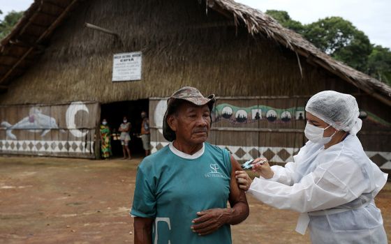 An Indigenous man receives the AstraZeneca/Oxford COVID-19 vaccine from a municipal health worker in the Sustainable Development Reserve of Tupe in Manaus, Brazil, Feb. 9. (CNS/Reuters/Bruno Kelly)