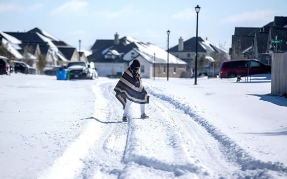 A man in Pflugerville, Texas, walks to his friend's house Feb. 15 in a neighborhood that had no electricity. (CNS/USA Today Network via Reuters/Austin American-Statesman/Bronte Wittpenn)